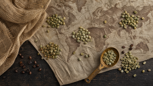 Overhead studio flatlay of green coffee beans grouped on a vintage world-map cloth with a brass scoop