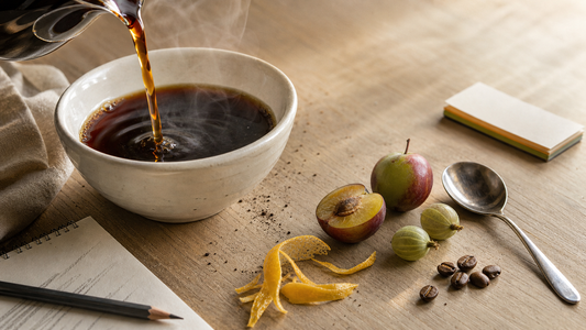 Coffee sensory still life with citrus, apple, black coffee, and cupping tools illustrating good acidity in coffee.